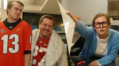 two guys in jerseys, one woman handing out a piece of paper